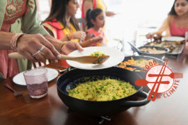 Indian women in saris serving and eating food at table. Credit: Barry Diomede / Alamy Stock Photo.