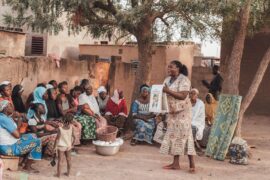 A woman from the health service shows villagers how to prevent malaria in Ouagadougou, Burkina Faso.