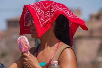 A woman with a portable fan covers her head from the soaring heat.