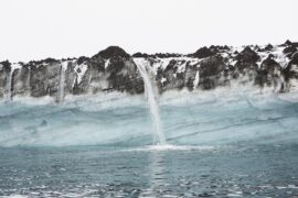 Snowmelt waterfall pouring over cliffs into ocean, Antarctic Peninsula, Weddell Sea, Antarctica.