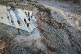 People in east Libya standing on a broken highway destroyed in recent heavy floods.