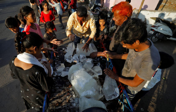 A man breaks a block of ice to distribute it among the residents of a slum during hot weather in Ahmedabad, India, April 28, 2022