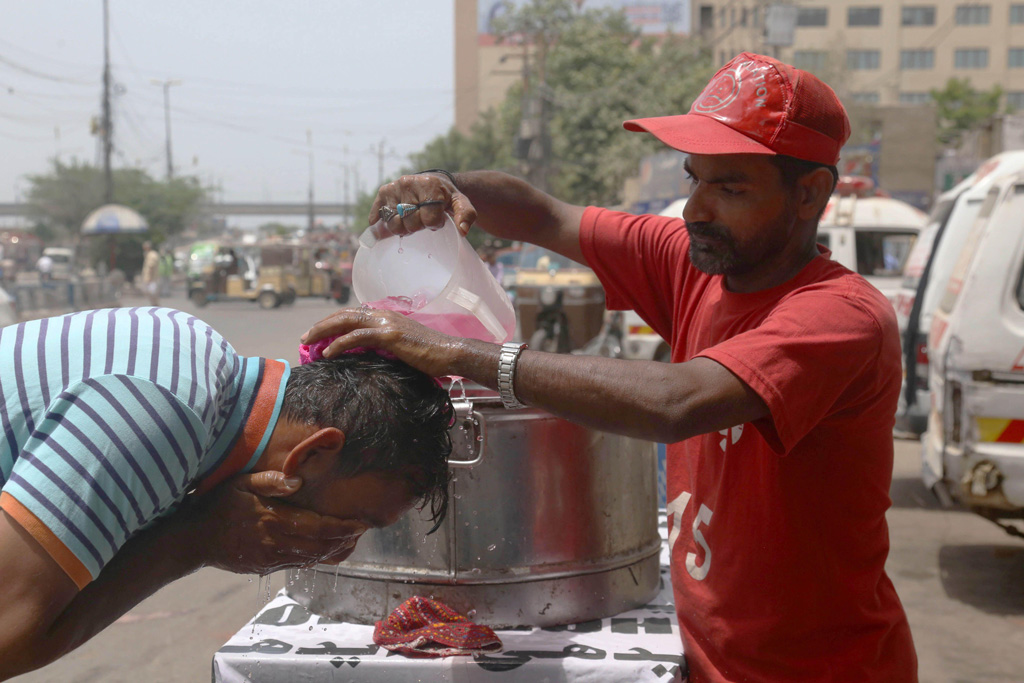 A volunteer pours water on a pedestrian during a heatwave in southern Pakistan, May 2022