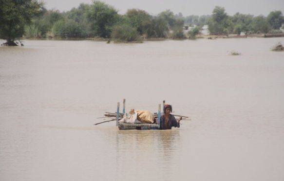 A woman carries her belongings through flood water in Rajanpur, Pakistan in August, 2022