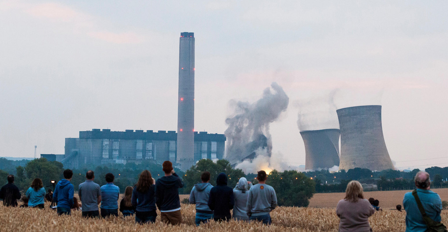 A field of people watch from a distance as the iconic cooling towers of Didcot A coal power station are demolished