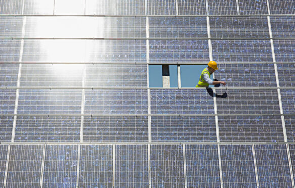 Worker examines solar panel.