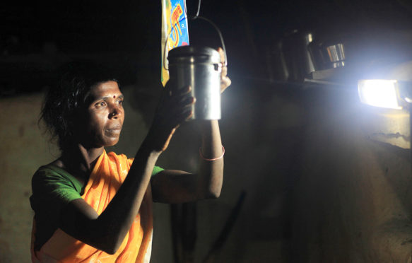 LED bulbs illuminate a woman as she does housework at night, Karnataka, India. Credit: ZUMA Press, Inc. / Alamy Stock Photo. D9RYDR