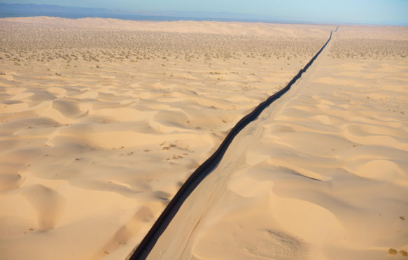 INTERNATIONAL BORDER: MEXICO - UNITED STATES (aerial view). Algodones Dunes in the Sonoran Desert, Baja California, Mexico (left of wall)