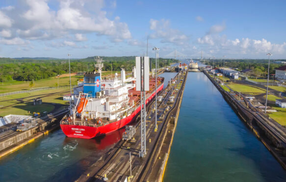 Red cargo ship transits through Gatun Locks, Panama Canal.