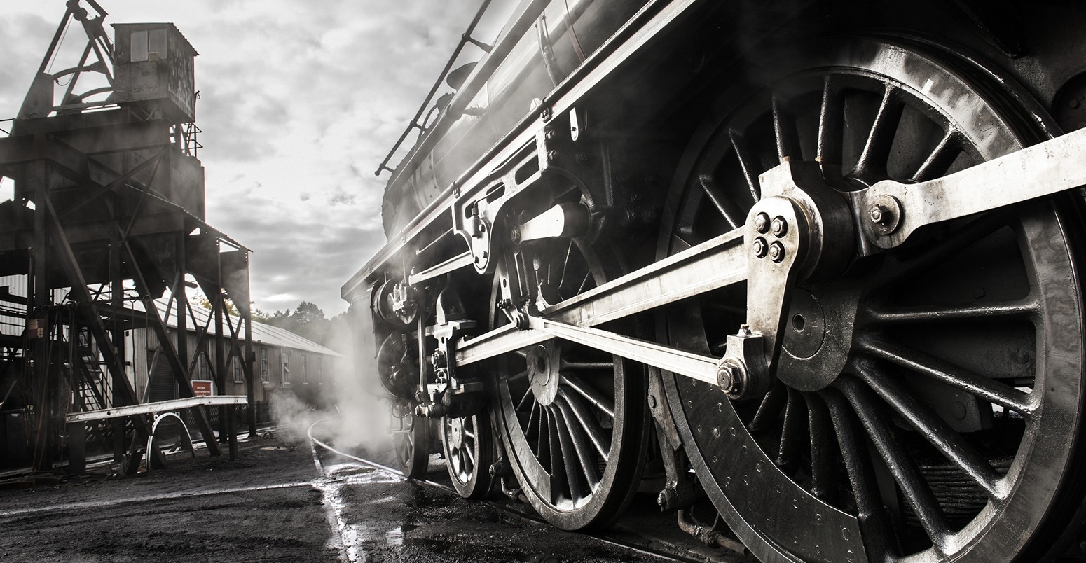 A steam train waiting to receive water from a water tower at a station in North Yorkshire.