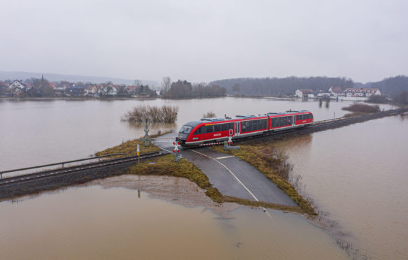 Train-passing-through-a-flooded-road-in-Germany,-February-2021