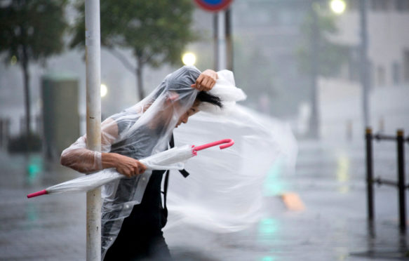 A woman clings on as typhoon Roke blows through Tokyo, Japan, 21 September 2011. Credit: Robert Gilhooly / Alamy Stock Photo. C7G6KM