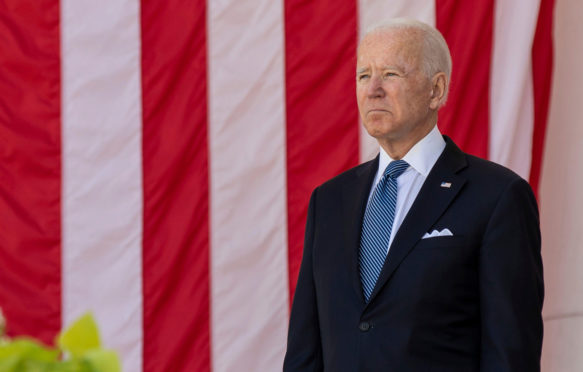 US President Joe Biden stands in front of the United States national flag