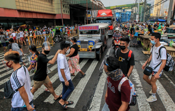 People wearing protective masks are seen at a busy street in Manila, March 2021